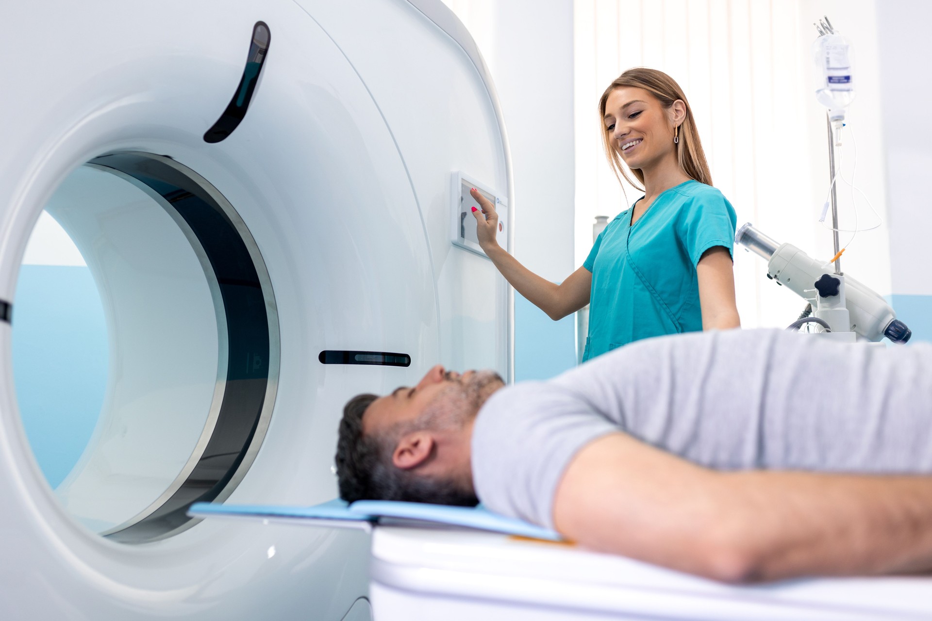 Female Doctor Looking At Patient Undergoing CT Scan. Doctor in uniform using tomography machine with lying patient in hospital